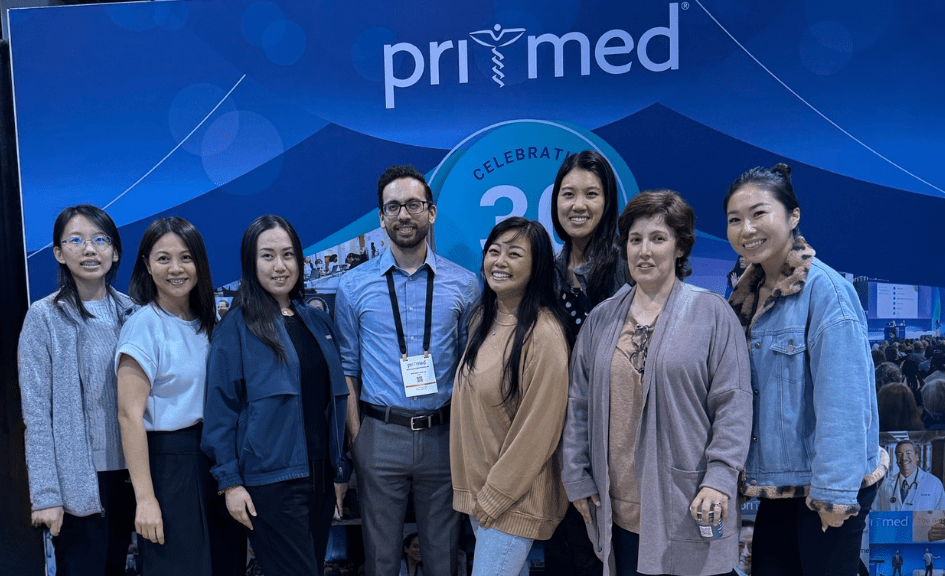 group of doctors posing in front of a Pri-Med sign at a conference